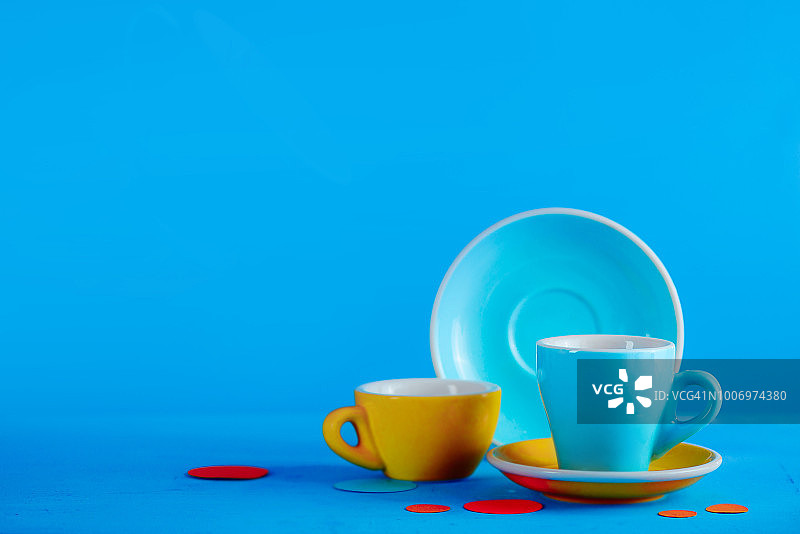鲜艳蓝色背景下的彩色咖啡杯图片素材