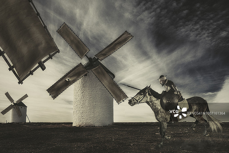 唐·吉诃德骑马冲向风车，幻想它们是巨人图片素材