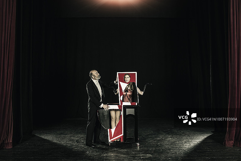 魔术师与助手表演魔术，助手在魔术箱中被切成两半图片素材