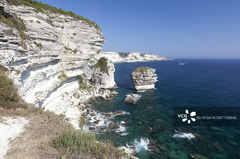 阳光照耀着绿松石色大海环绕的白色石灰岩悬崖（法国科西嘉博尼法乔，地中海，欧洲）图片素材