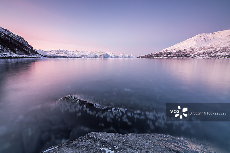 挪威卡菲尤尔峡湾：夕阳下冰封海面映衬粉色天空与雪峰图片素材