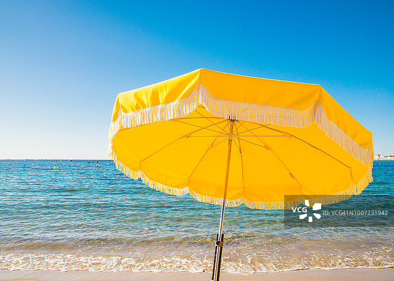 蓝色天空下，法国蓝色海岸胡安莱潘的巨型黄色海滩遮阳伞图片素材