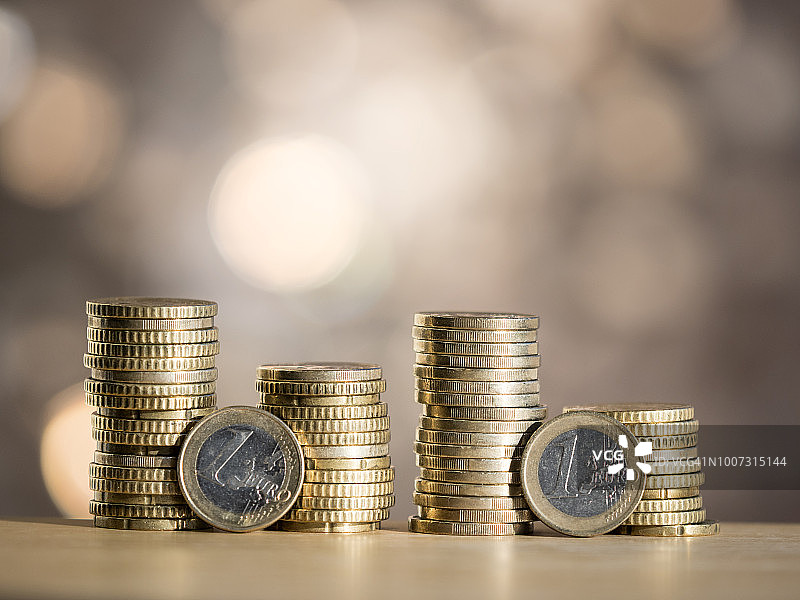 阳光下，堆放在桌子上不同大小的欧元硬币图片素材