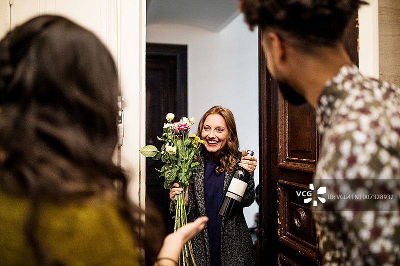 拜访朋友时手捧花束和葡萄酒瓶的女人图片素材