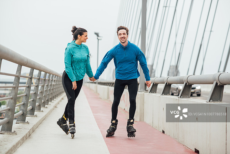 幸福情侣在桥上牵手滑旱冰图片素材