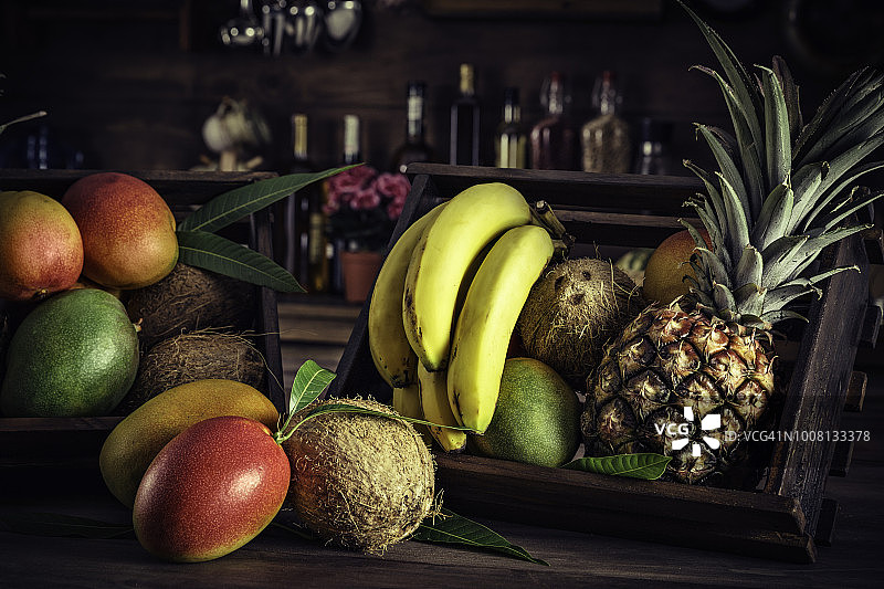 乡村厨房中装满各种热带水果的木箱，自然光图片素材