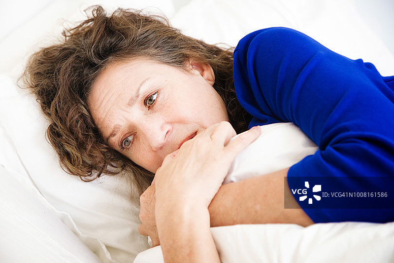 悲伤的年长妇女肖像在床上拥抱她的枕头图片素材
