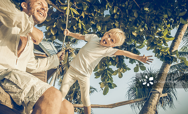 父子在秋千上享受夏日阳光图片素材