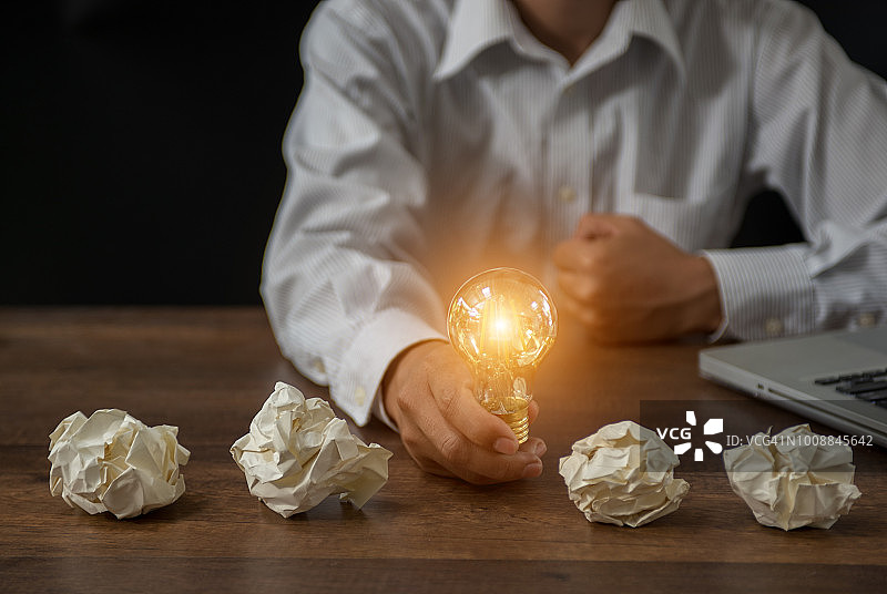 商人拿着发光灯泡的手，创意、创新和灵感概念图片素材