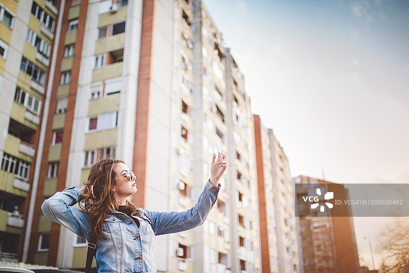 在建筑物前玩耍并自拍的美丽白人女性图片素材
