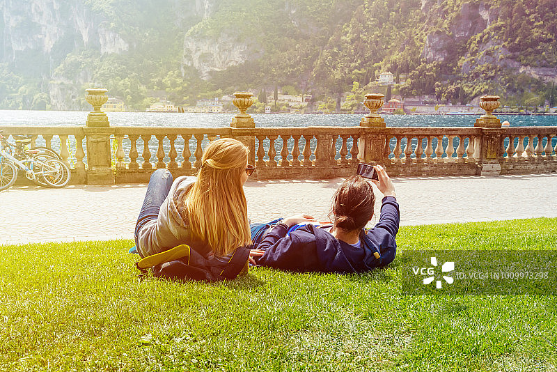 情侣在意大利科莫湖岸边的草地上自拍图片素材