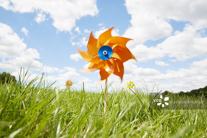 草地上对着天空的橙色风车图片素材