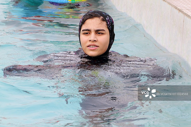 戴着头巾在游泳池游泳的巴基斯坦女孩图片素材