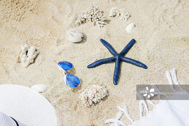 巴拉望海滩沙滩上的各种石头、蓝色海星、蓝色太阳镜、白色帽子和围巾图片素材