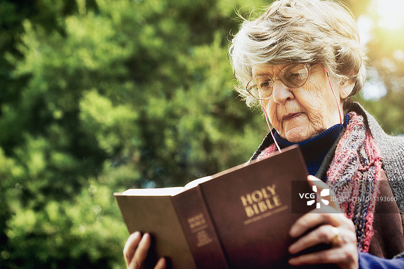 白发老妇人在花园里读圣经图片素材