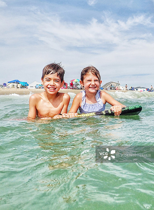 兄妹在特拉华州贝瑟尼海滩的海中漂浮图片素材