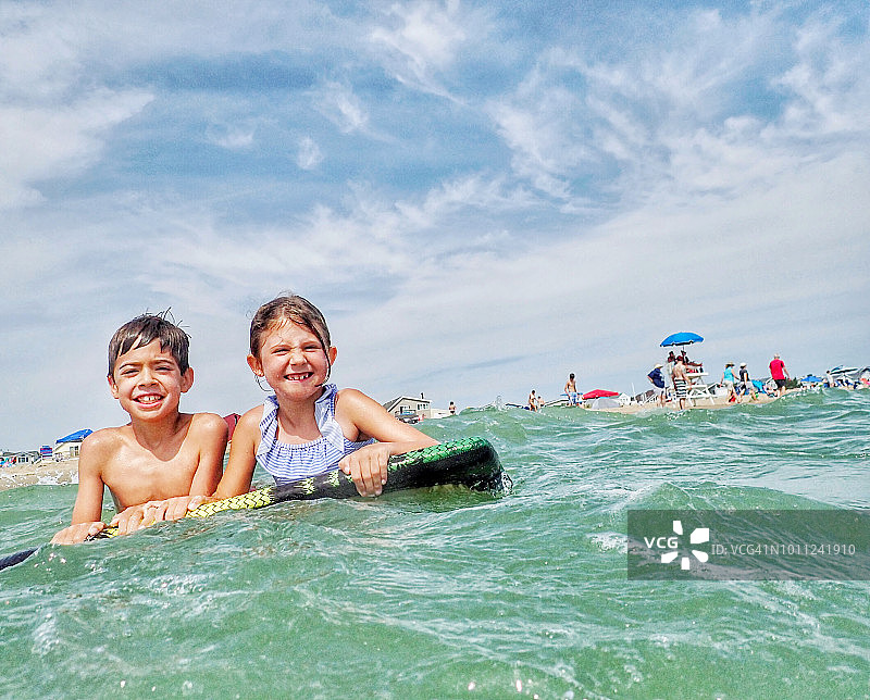 兄妹在特拉华州贝瑟尼海滩玩浮板图片素材