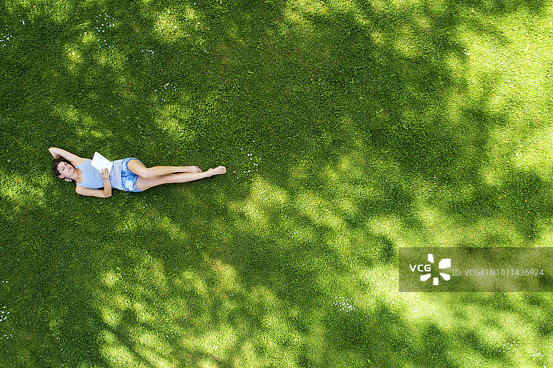 年轻女子躺在草地上使用平板电脑图片素材