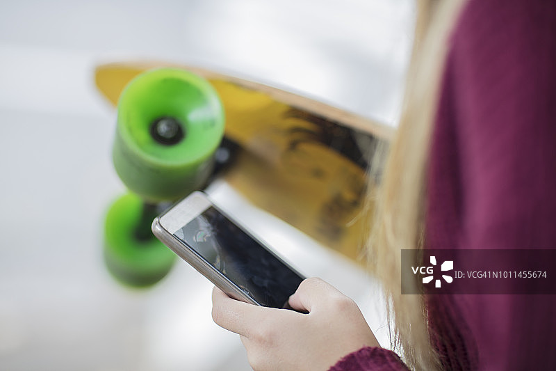 少女手持滑板和手机特写图片素材