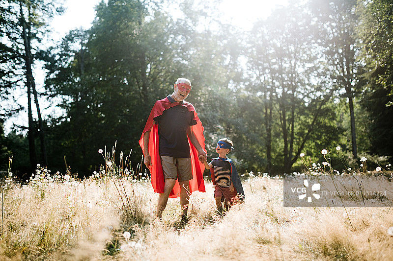 爷爷装扮成超级英雄和孙子在户外玩耍图片素材