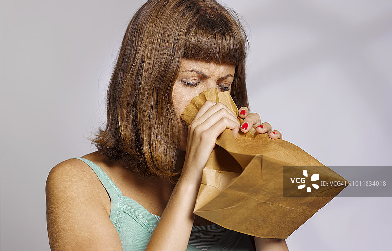 女子对着纸袋过度换气图片素材