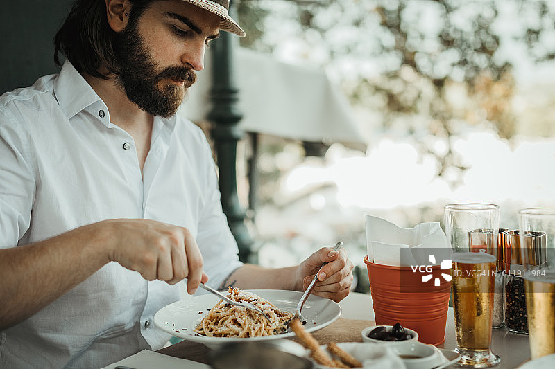 在阳光明媚的餐厅里享受美食的年轻男子图片素材