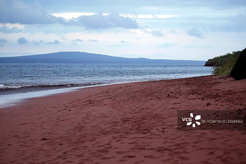红色沙滩与远处的火山图片素材