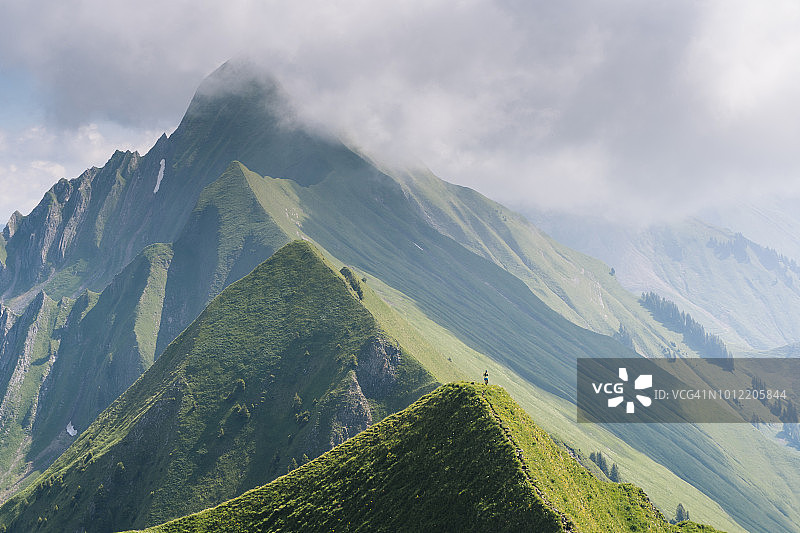 越野跑者沿着远处山脊上的高山小径前进图片素材