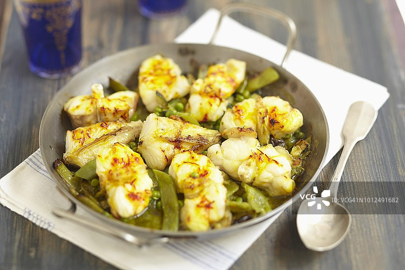 安康鱼、绿色蔬菜和藏红花塔吉锅图片素材