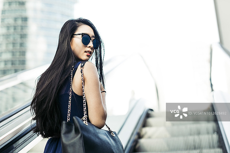 年轻女商人乘坐自动扶梯图片素材
