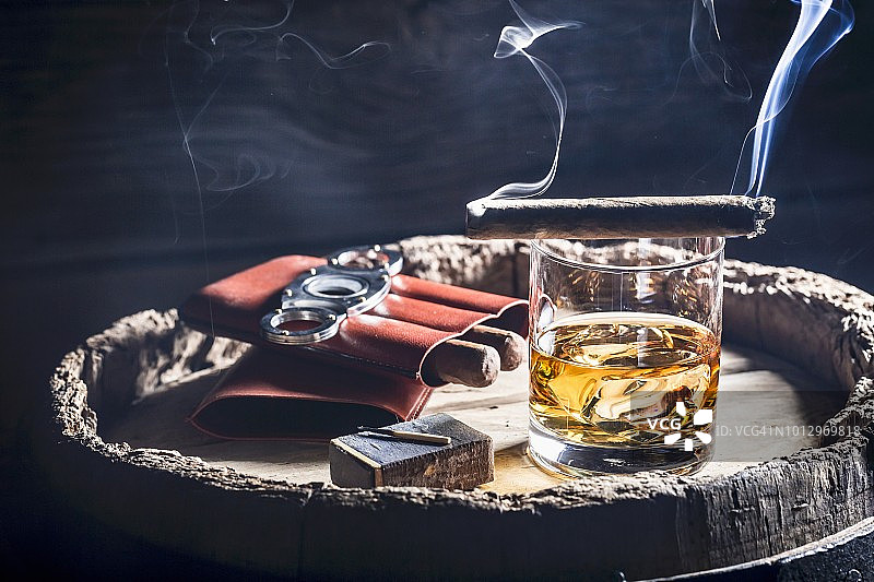 威士忌酒杯旁的冒烟雪茄图片素材
