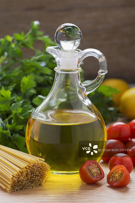 木桌上的橄榄油、番茄、欧芹和意大利面图片素材