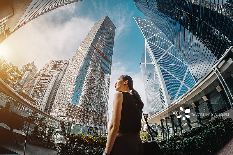 站在中央商务区高层金融大厦前，自信地仰望天空的亚洲女商人图片素材