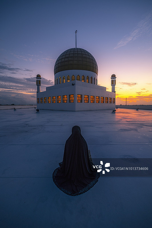 穆斯林祈祷，清真寺在前景中，日落景象图片素材