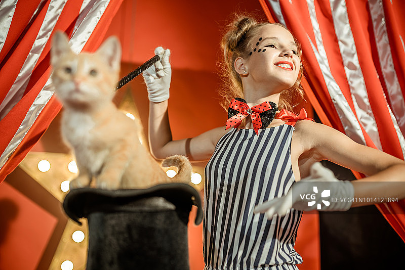快乐女孩表演魔术，小猫从帽子出现图片素材