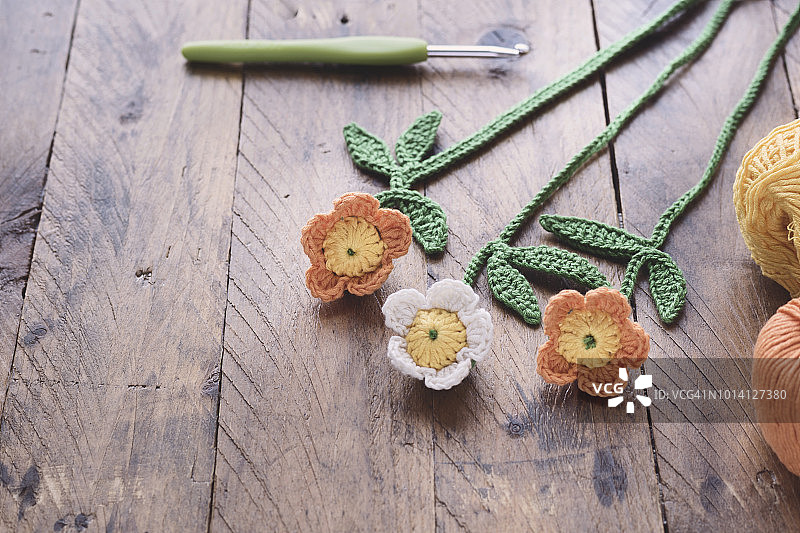 乡村木质背景中的手工钩针雏菊、钩针和毛线球，选择性聚焦和留白图片素材