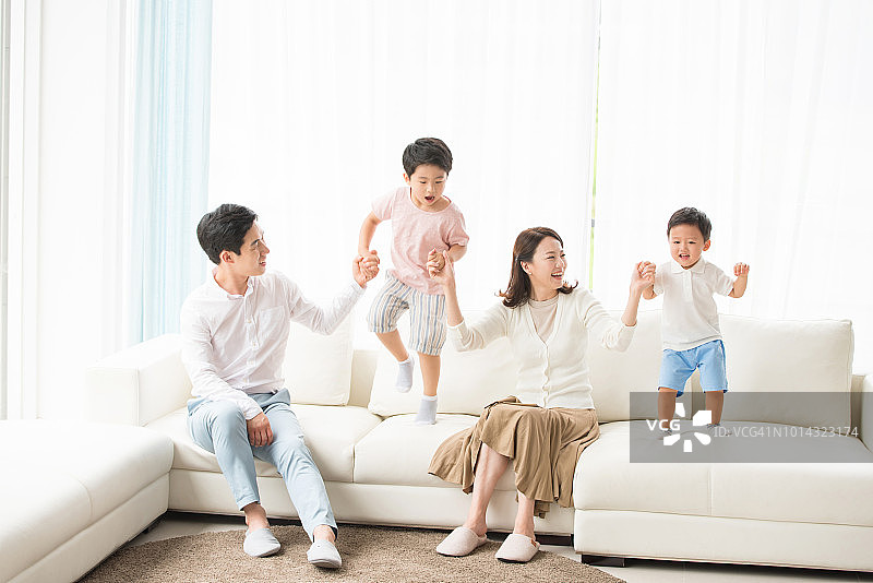 孩子们和家人玩得很开心，在沙发上跳跃图片素材