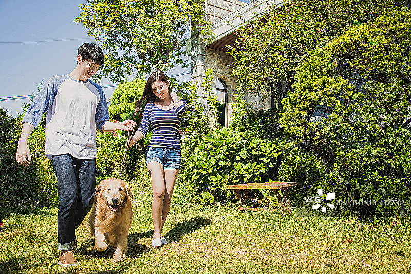 一对夫妇和狗在院子里散步图片素材