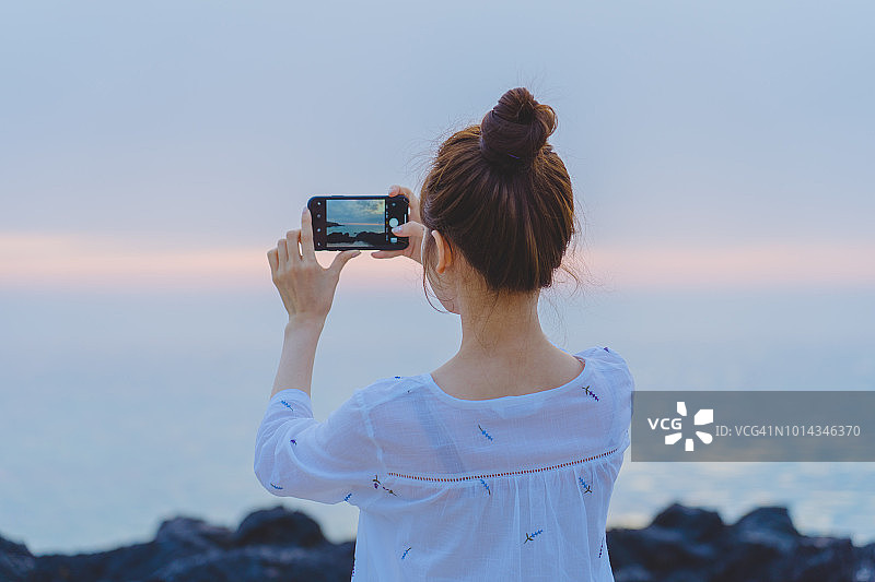女人拍摄海上日落美景图片素材