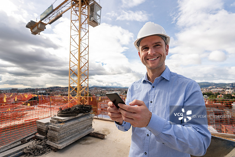 快乐的建筑师在建筑工地发短信图片素材