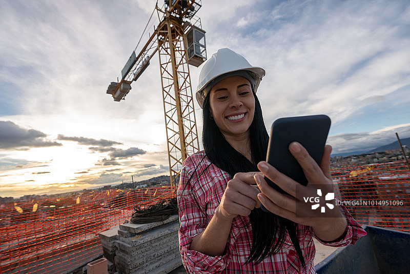 快乐的工程师在建筑工地发短信图片素材