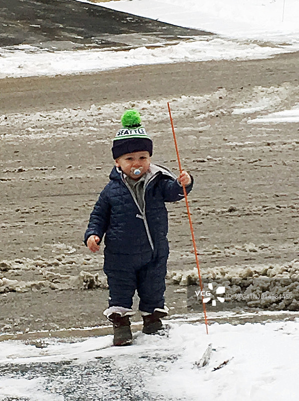 穿着滑雪服站在泥泞路上的幼儿图片素材