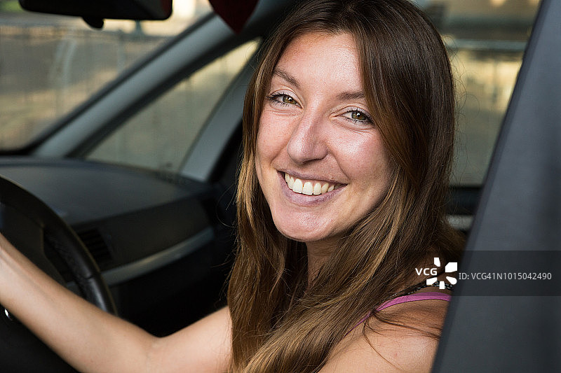 年轻女人开车，微笑看着镜头图片素材
