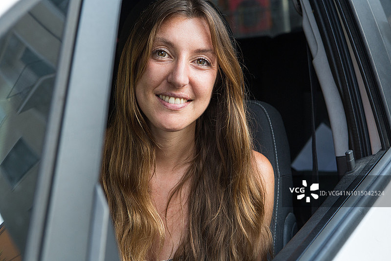 年轻女人开车，微笑看着镜头图片素材