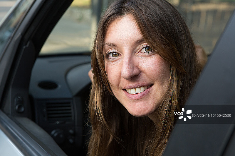 年轻女人开车，微笑看着镜头图片素材