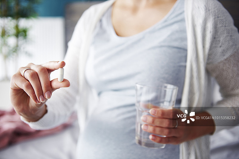 手拿胶囊的孕妇，波兰德比察图片素材