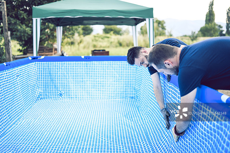 搭建户外儿童泳池的英俊男工人图片素材