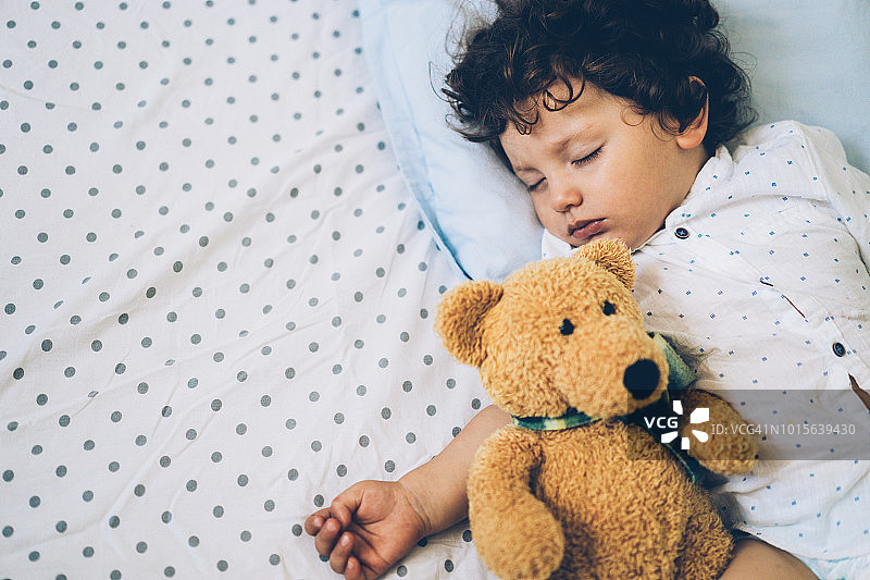 抱着泰迪熊睡觉的幼儿图片素材