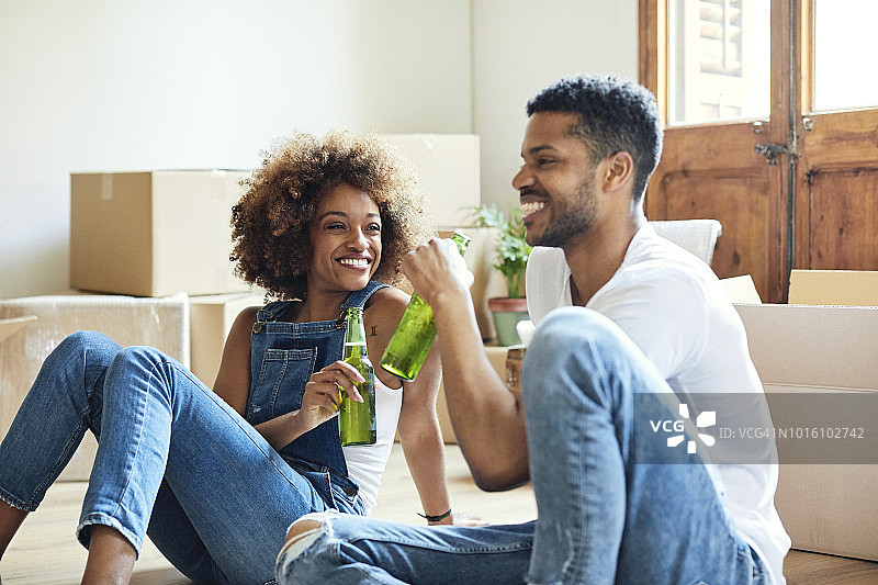 在新房里喝啤酒的微笑情侣图片素材