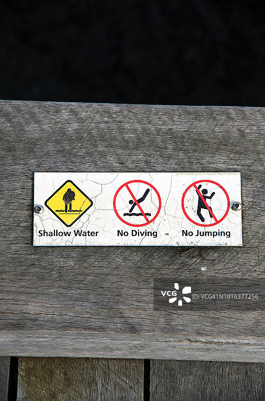 码头边缘的安全警告标志，上面写着“水浅”、“禁止潜水”和“禁止跳跃”图片素材
